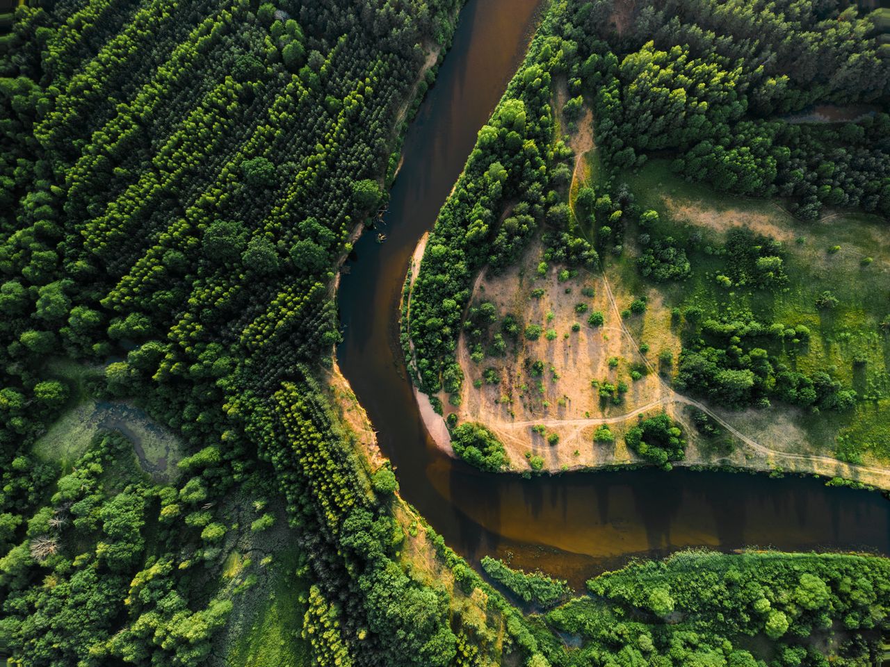A breathtaking aerial view of a winding river through lush forests in Vileyka, Belarus.